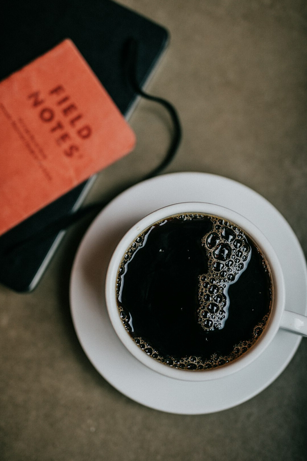 Notebook and pen on a wooden desk with coffee cup